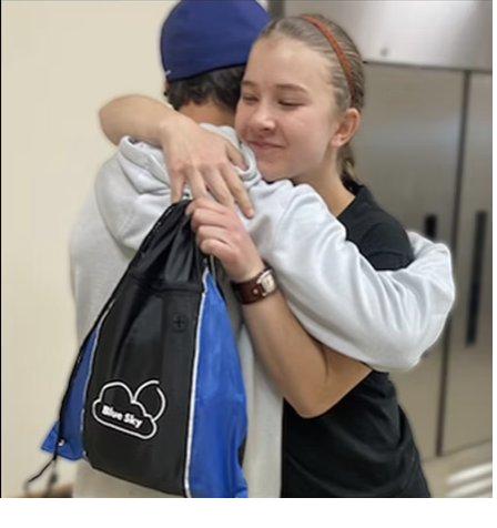 A survivor embracing a volunteer while holding a Blue Sky relief kit